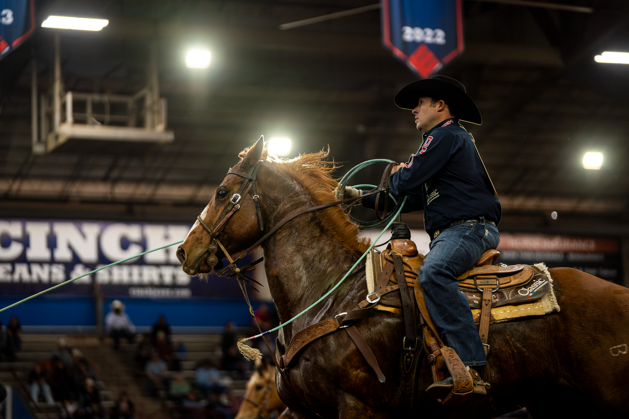A team roper on horseback holding a Classic Rope in the arena